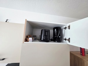 Eine Küchenzeile mit integrierter Kaffeemaschine und einer Kapselbox.