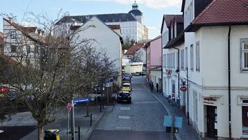 A cobblestone street lined with buildings, a white van parked on the side, and a clear sky.