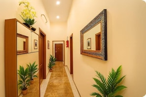 A hotel hallway with mirrors, potted plants, and a fire extinguisher. - RELAX Palace (Roma)