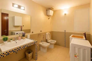 A bathroom with a sink, two toilets, a mirror, and a trash bin. - RELAX Palace (Roma)