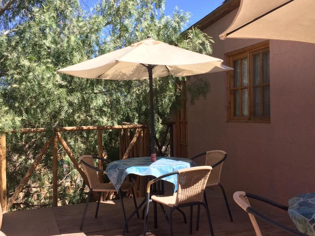 Une terrasse extérieure avec une table et des chaises, un grand parasol et une clôture en bois.