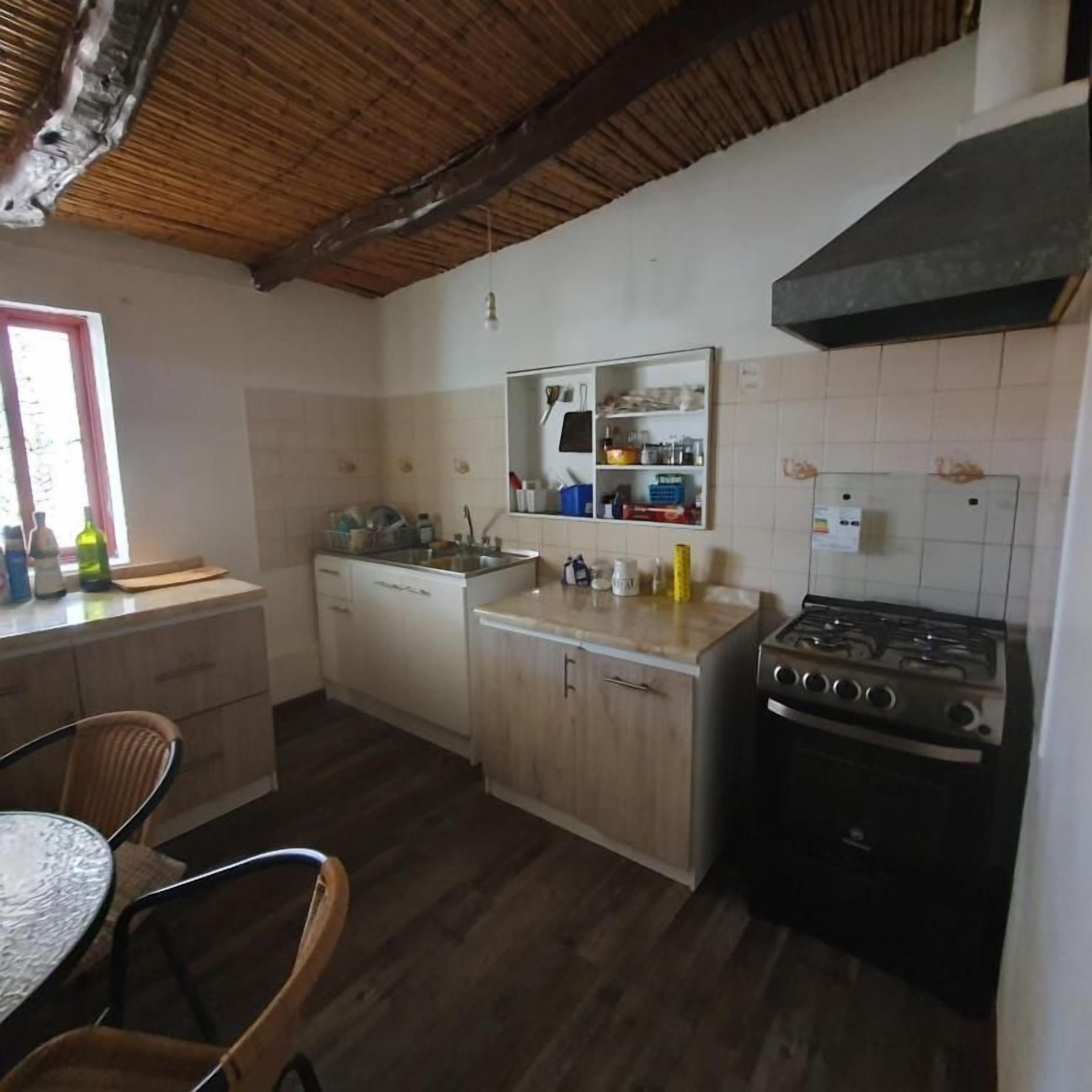 A compact kitchen with a wooden ceiling, a gas stove, and a built-in sink.