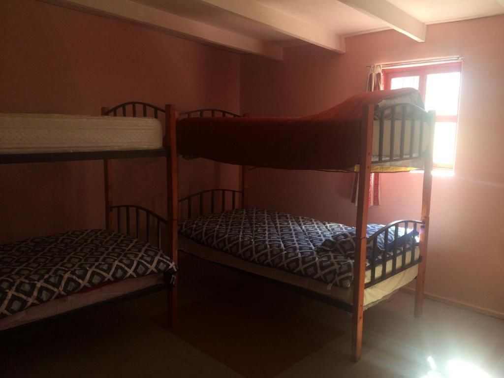 Una habitación con literas, una ventana y una puerta.