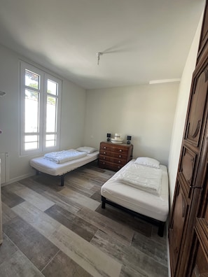 A bedroom with two single beds, a wooden dresser, and a ceiling fan. - New Listing (Saint-Brevin-les-Pins)
