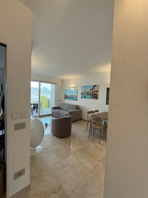 Un vaste espace de vie comprenant un canapé, un pouf et une table à manger.