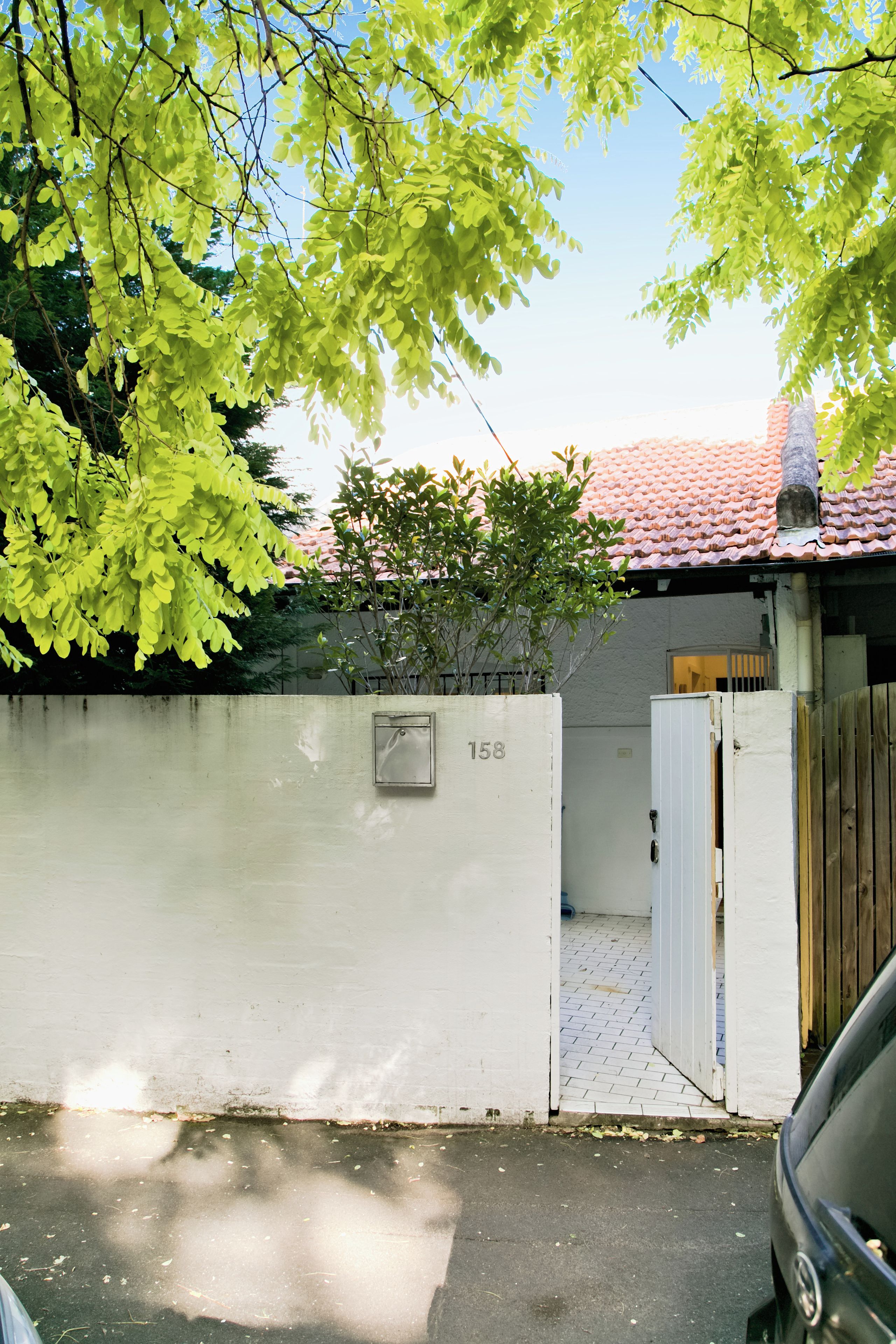 Ett inhägnat bostadsområde med en vit mur, en grind av metall och ett registreringsskylt.