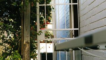 A white metal gate with a decorative top, a brick wall, and a window with blinds.