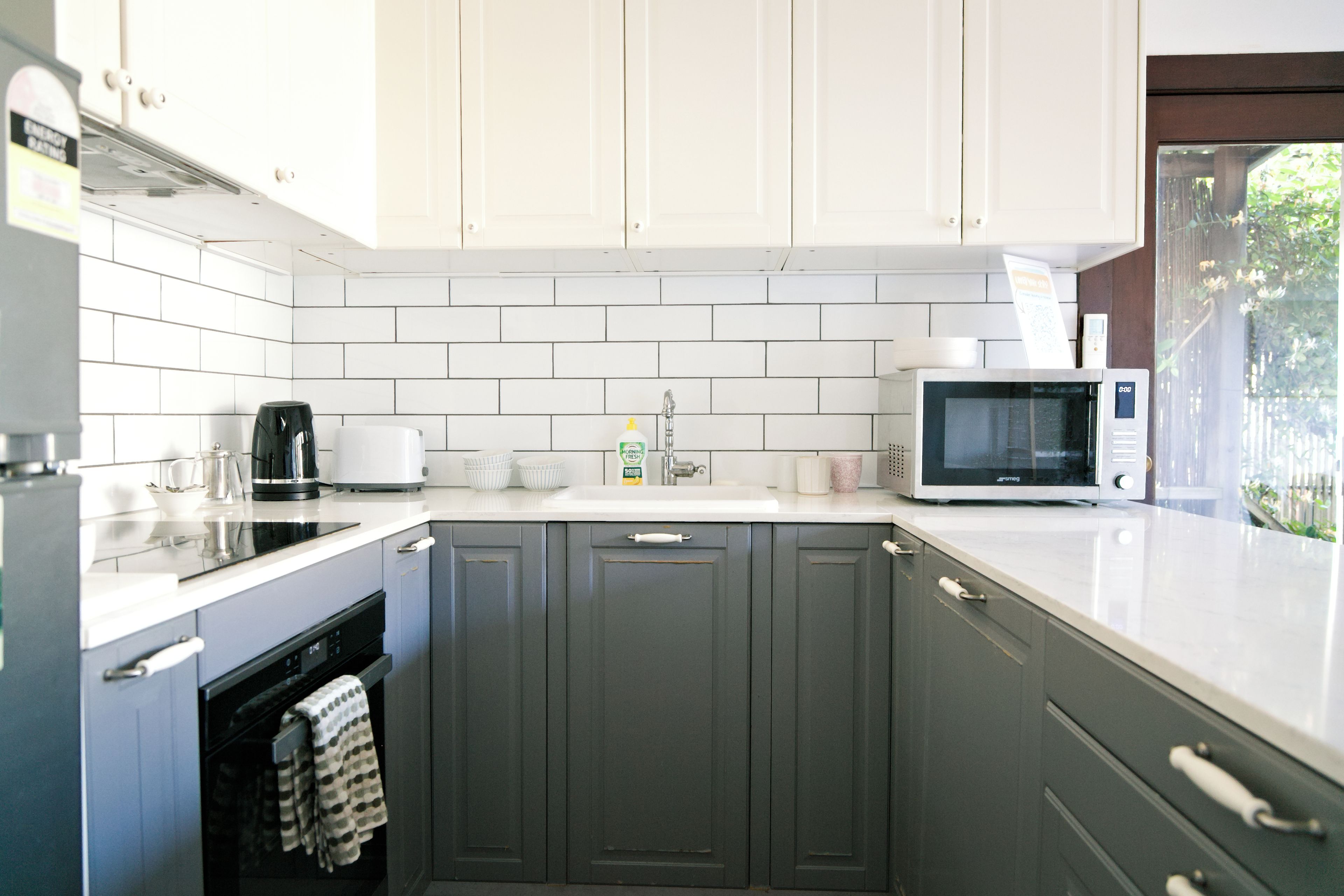 A kitchen with white cabinets, a microwave, a coffee maker, and a sink.
