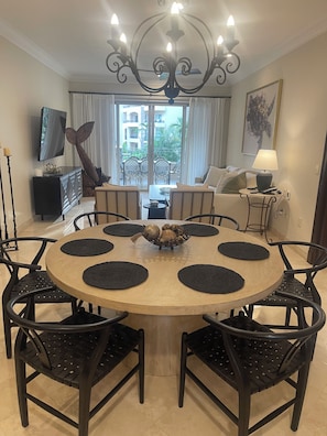 Zona pranzo con tavolo rotondo, sedie nere e lampadario.