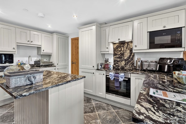 A modern kitchen with white cabinetry, a marble countertop, and stainless steel appliances. - Pansy Lodge, this two-bedroom barn conversion sleeps 6. (Mydroilyn)