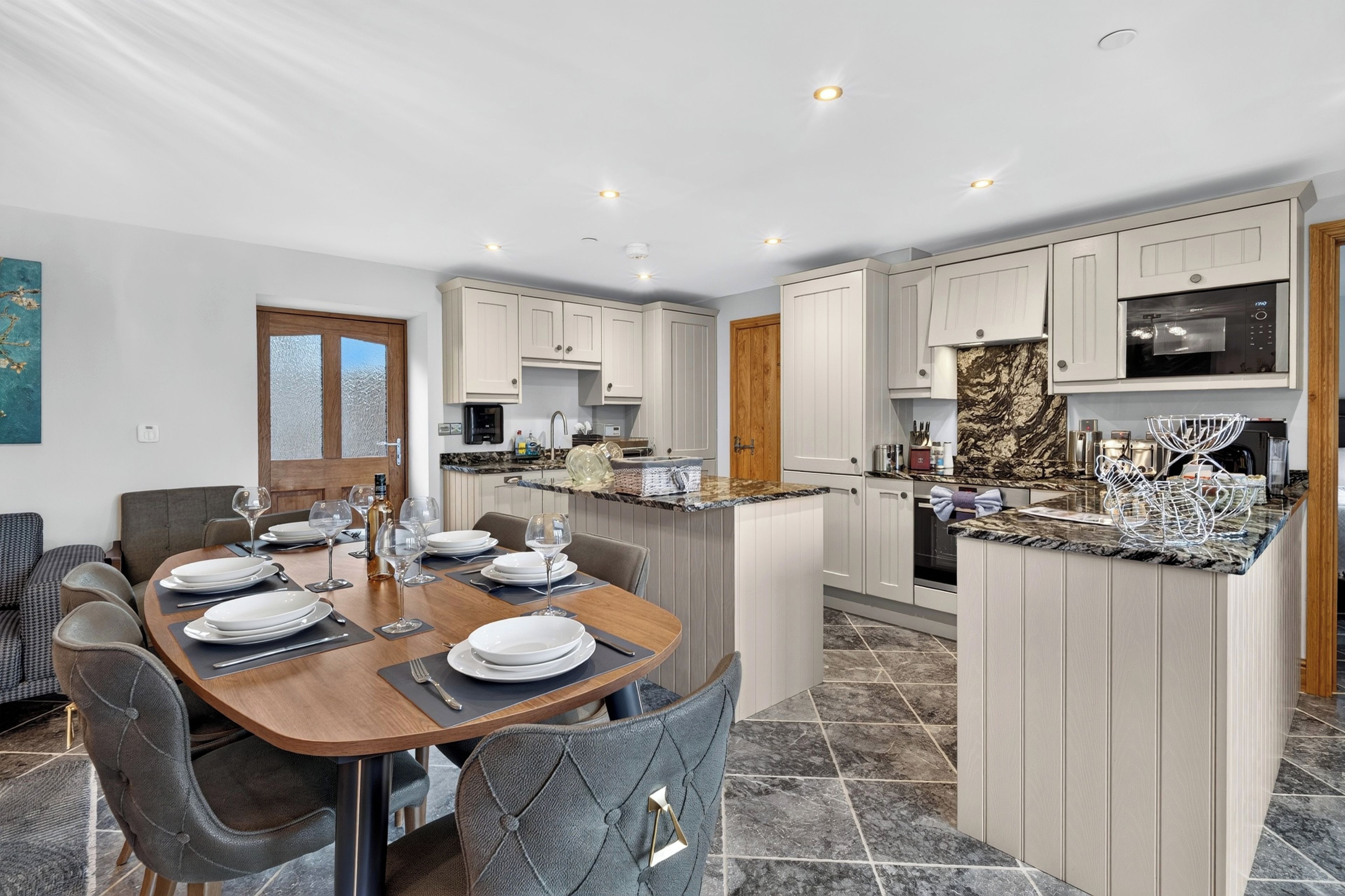 A modern kitchen with white cabinetry, a central island, and a dining area with a wooden table set for a meal.