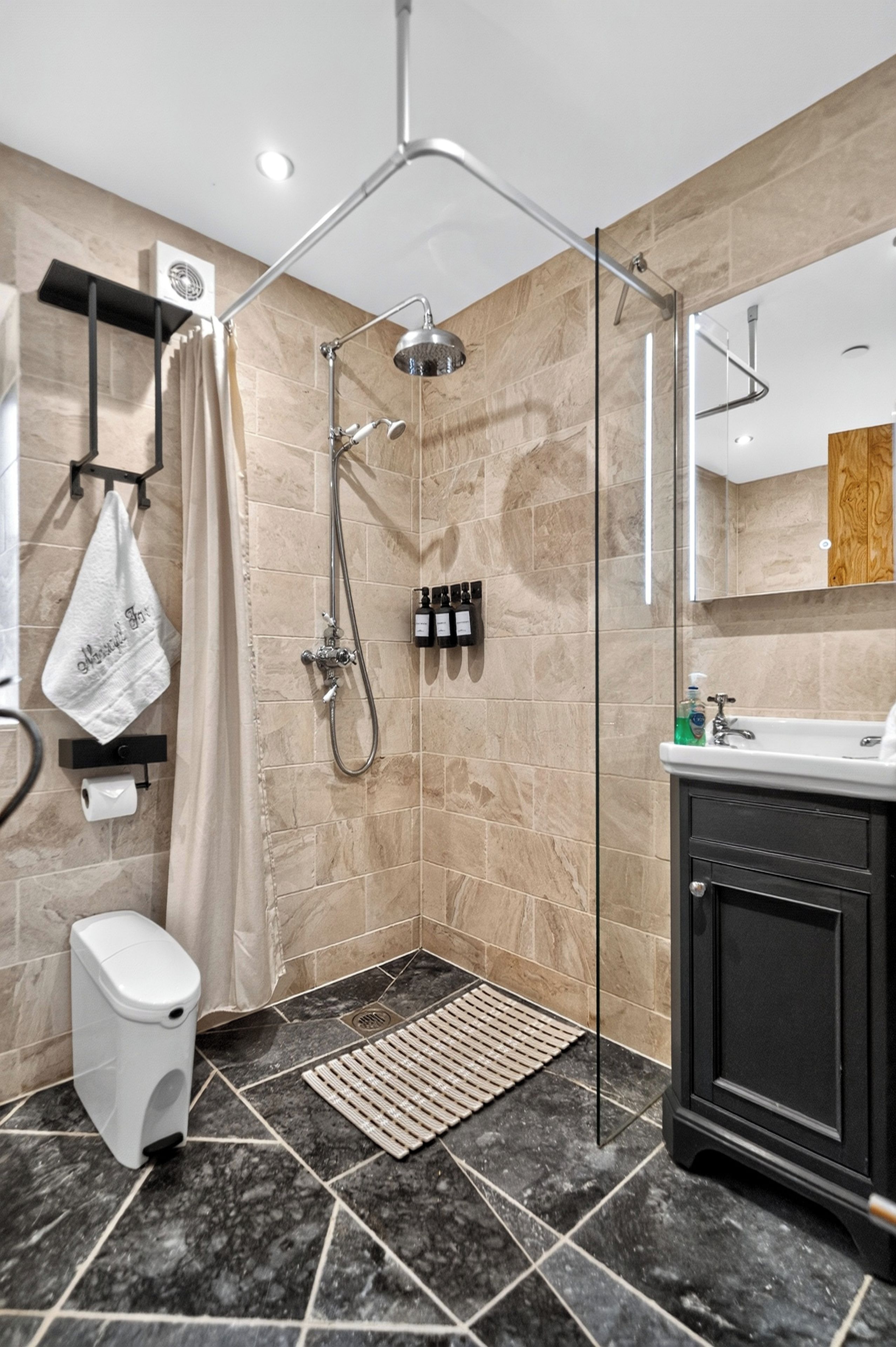 A modern bathroom with a glass-enclosed shower, a toilet, a sink, and a mirror.