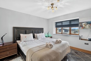 A bedroom with a bed, a nightstand, a lamp, a window with a view, and a painting on the wall. - Pansy Lodge, this two-bedroom barn conversion sleeps 6. (Mydroilyn)