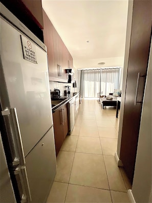Una cocina con refrigerador, gabinetes y un comedor con mesa y sillas.