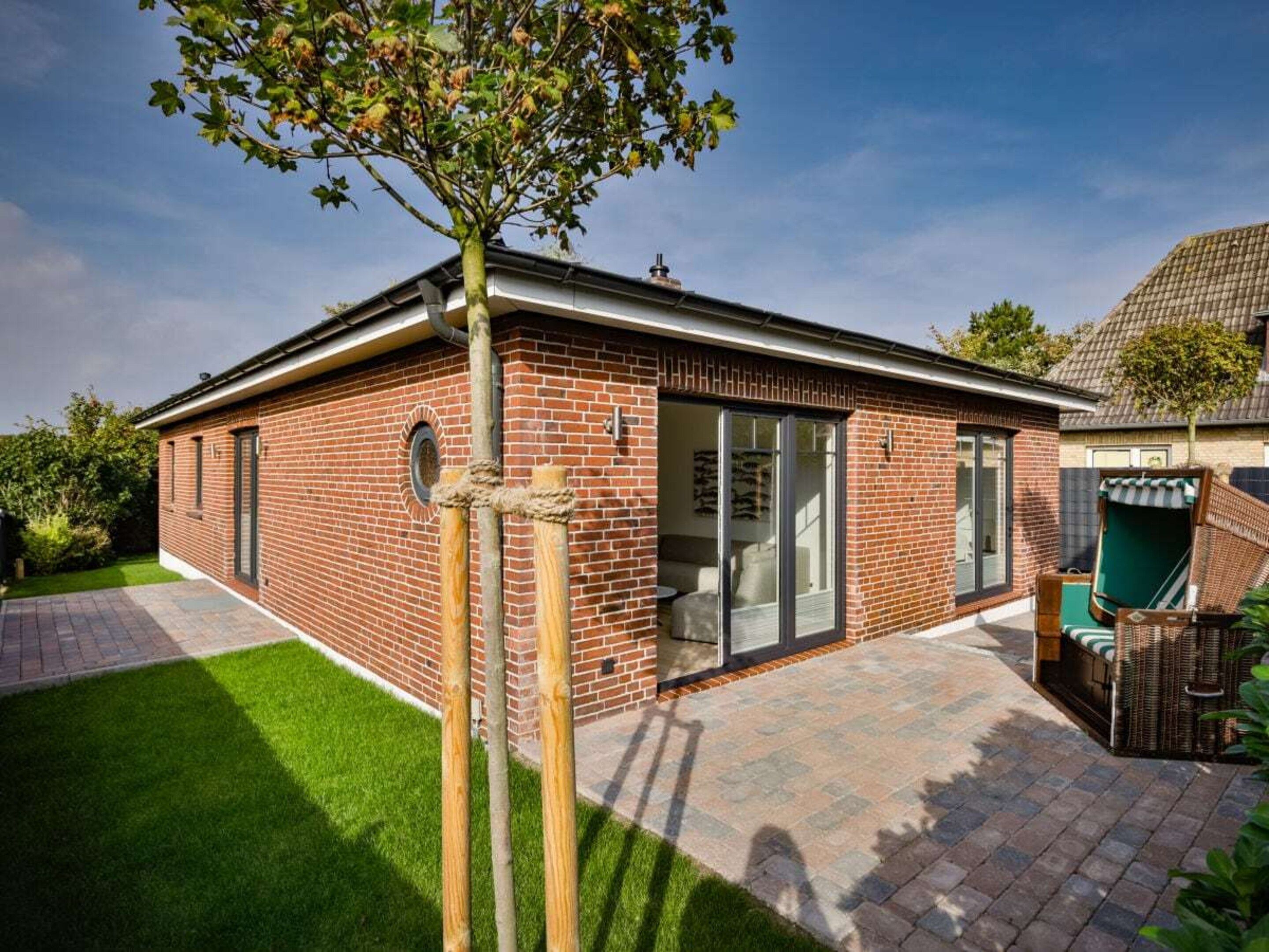 A brick house with a patio, a tree, and a clear sky.