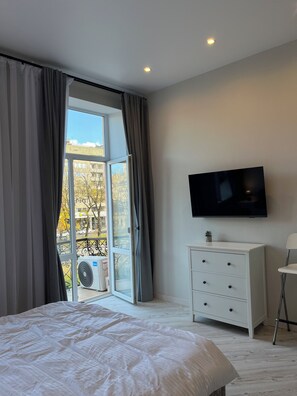 A bedroom with a bed, a dresser, a TV, and a window with curtains. - Beautiful apt. on Svobody avenue 7 Lviv (L'viv)