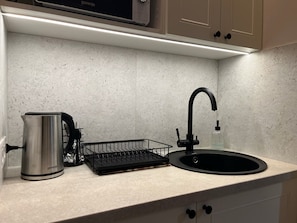 A kitchen with a stainless steel kettle, a black dish rack, and a black faucet. - Beautiful apt. on Svobody avenue 7 Lviv (L'viv)