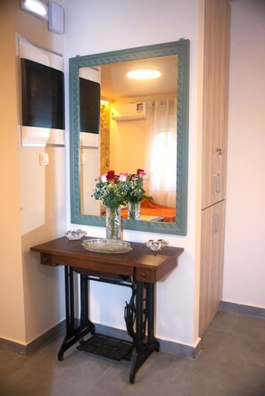 Une pièce comprenant une console en bois, un miroir et un vase avec des fleurs.
