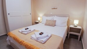 Une chambre d’hôtel avec un lit, deux tables de chevet avec des lampes, une porte et des serviettes sur le lit.