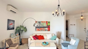 A living room with a sofa, coffee table, and a chandelier. - New Listing (Sainte-Maxime)