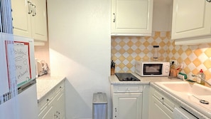 A compact kitchen with white cabinets, a microwave, and a small trash bin. - New Listing (Sainte-Maxime)