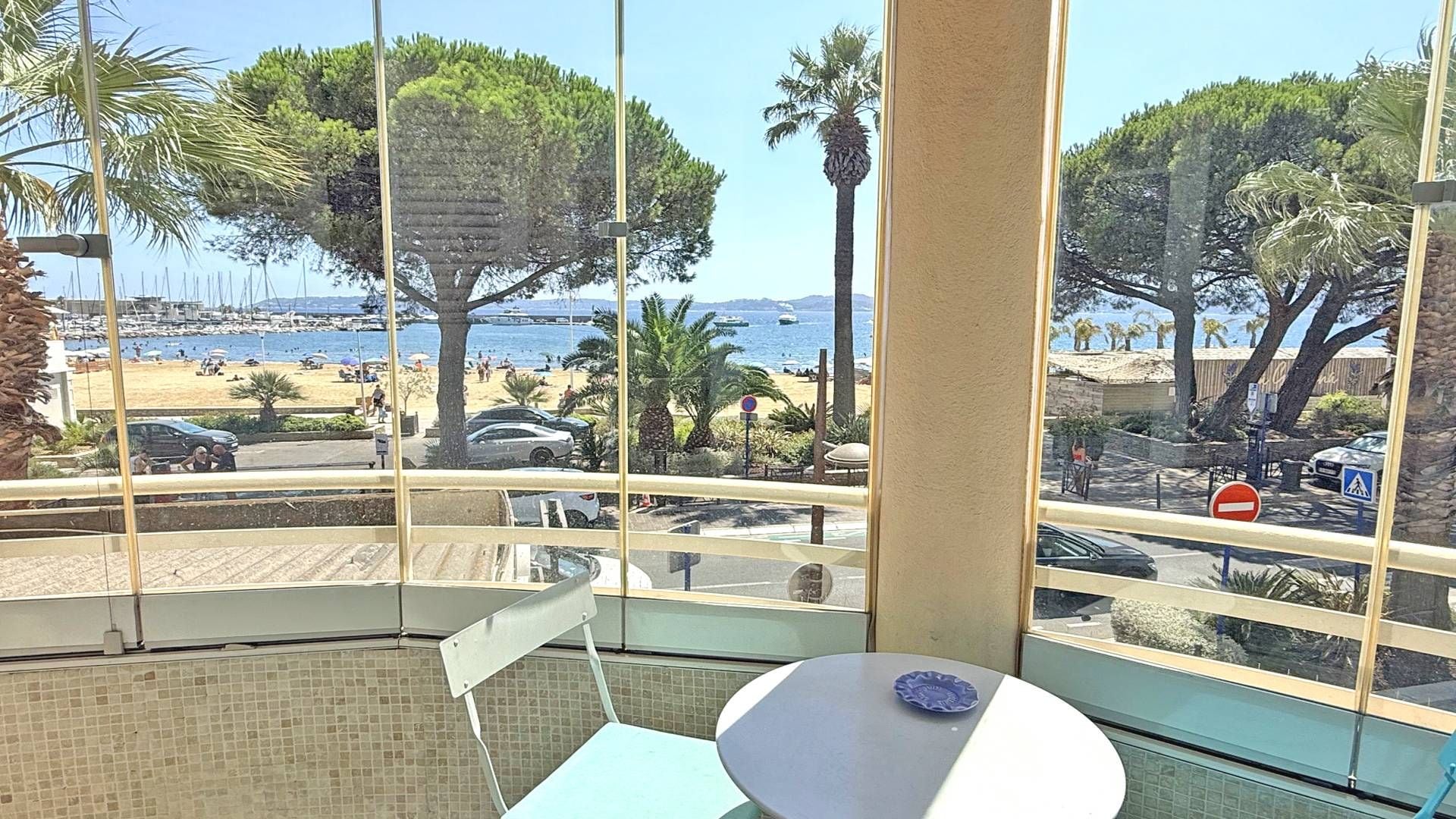 A room with a view of a beach, a table, and chairs.