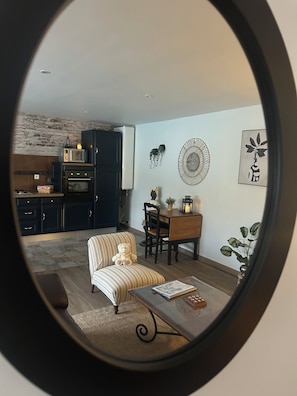 A kitchen with dark cabinets, a microwave, and a stove. There is a dining area with a table and chairs, a teddy bear, and a small plant. - New Listing (Argences)