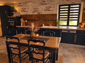 A kitchen with dark cabinets, a wooden dining table, and chairs. - New Listing (Argences)