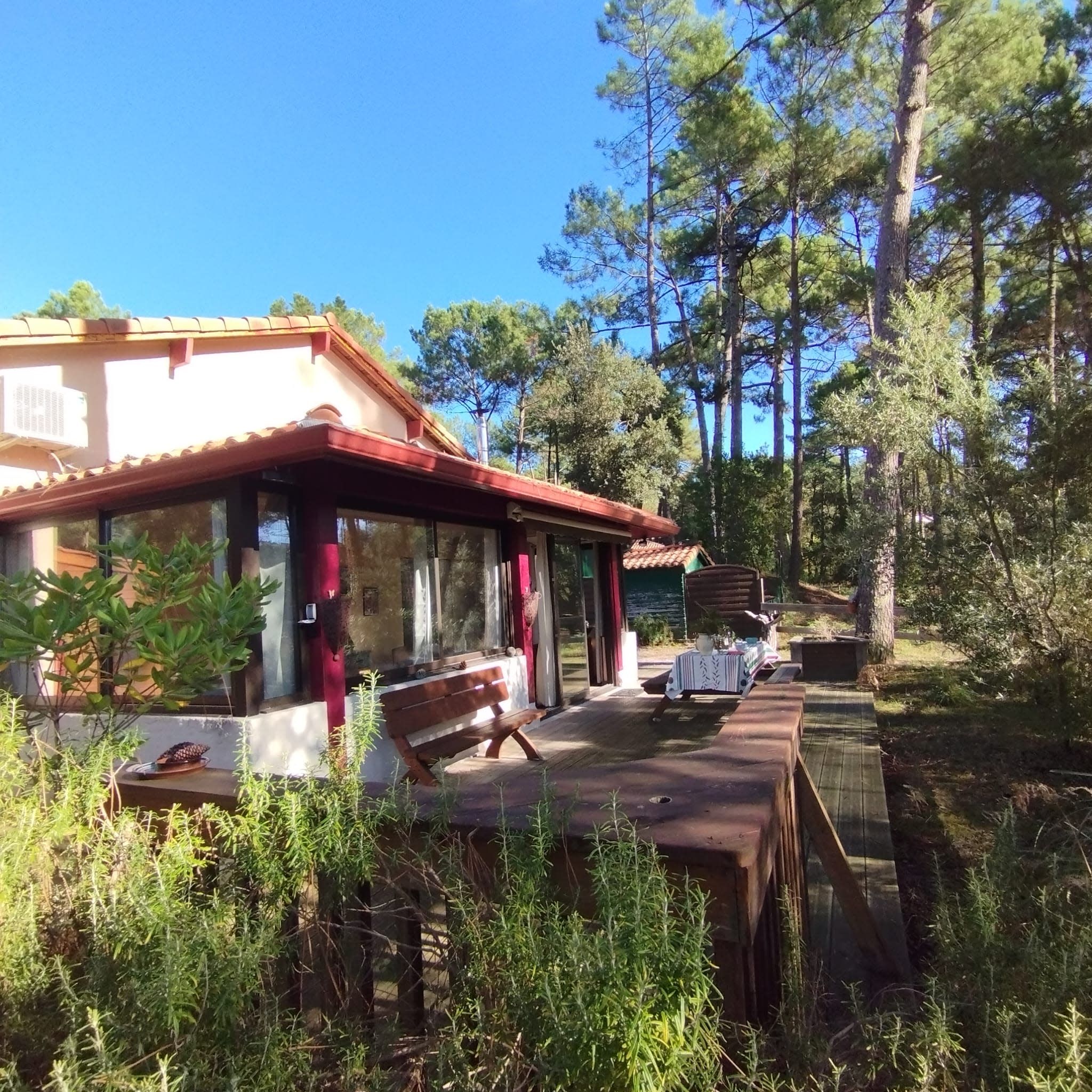 Une maison de campagne avec une terrasse en bois, un banc et une table.