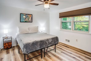 A bedroom with a bed, a ceiling fan, a window with blinds, and a painting on the wall. - Hot Tub Haven with Game Room Home with In-Law Suite (Rochester)
