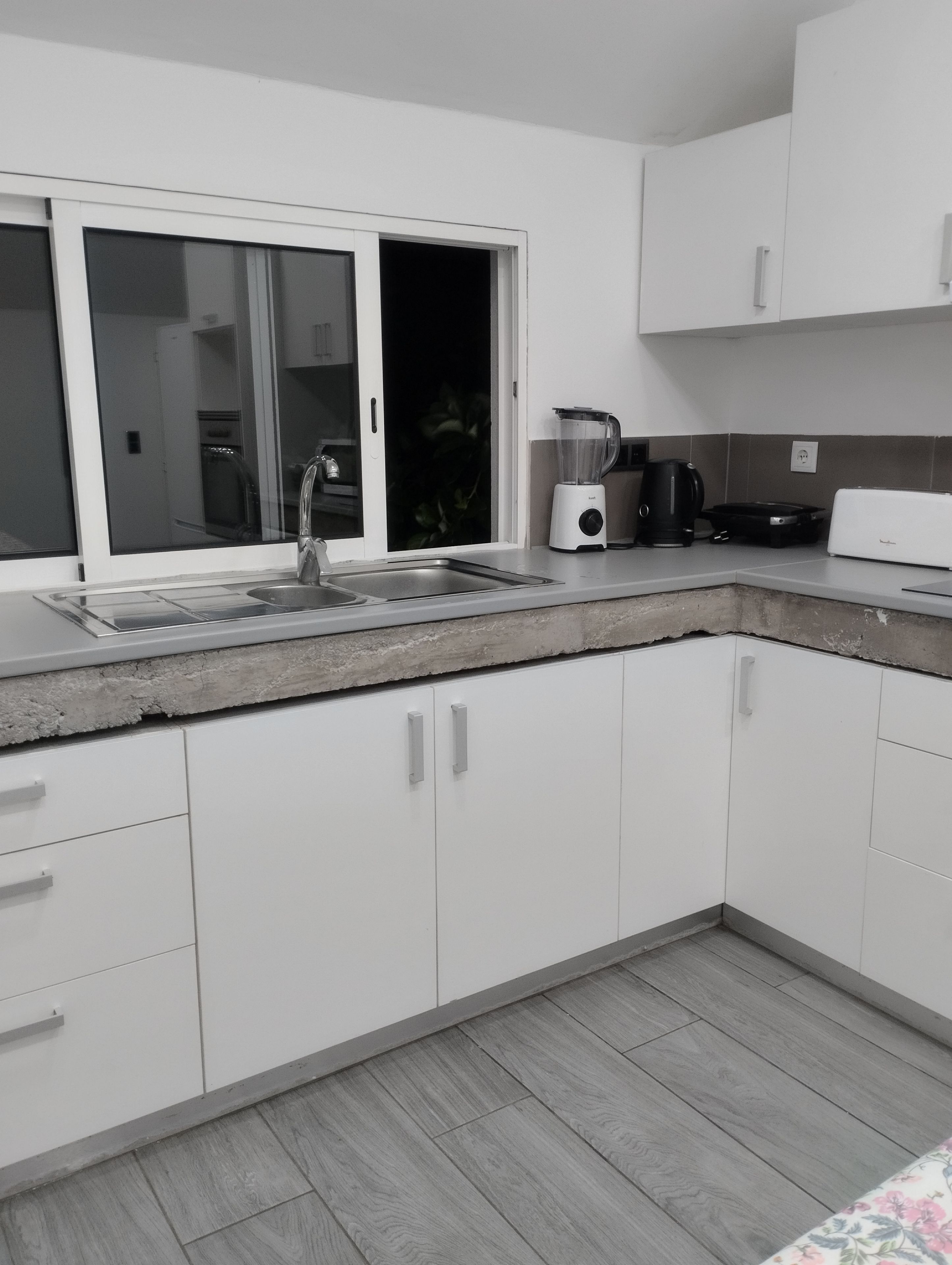 Una cocina moderna con armarios blancos, un lavamanos integrado, una licuadora y un tostador.