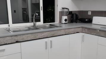 Una cocina moderna con armarios blancos, un lavamanos integrado, una licuadora y un tostador.