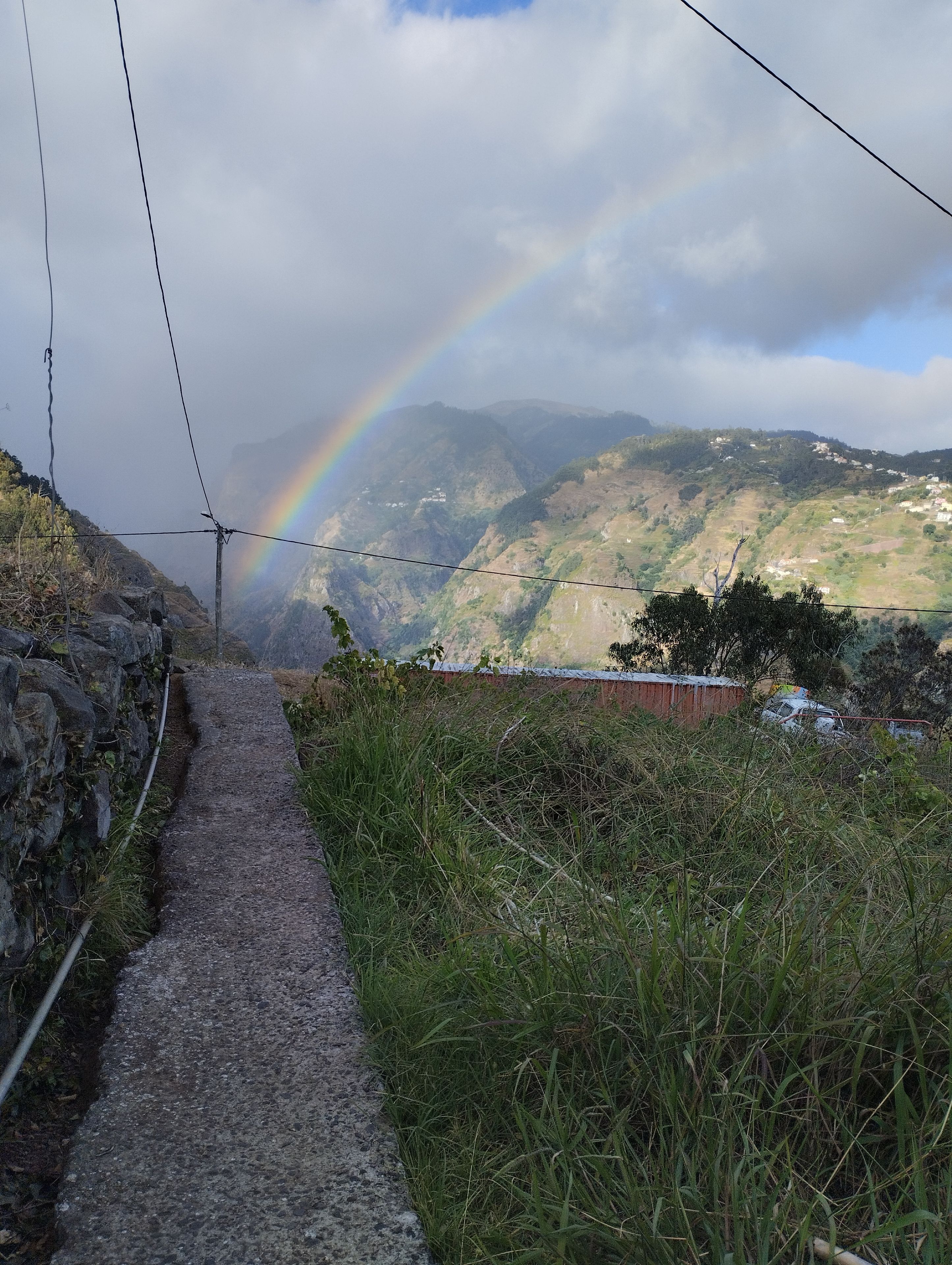 Un sentier qui mène à un paysage montagneux, avec un arc-en-ciel en toile de fond.