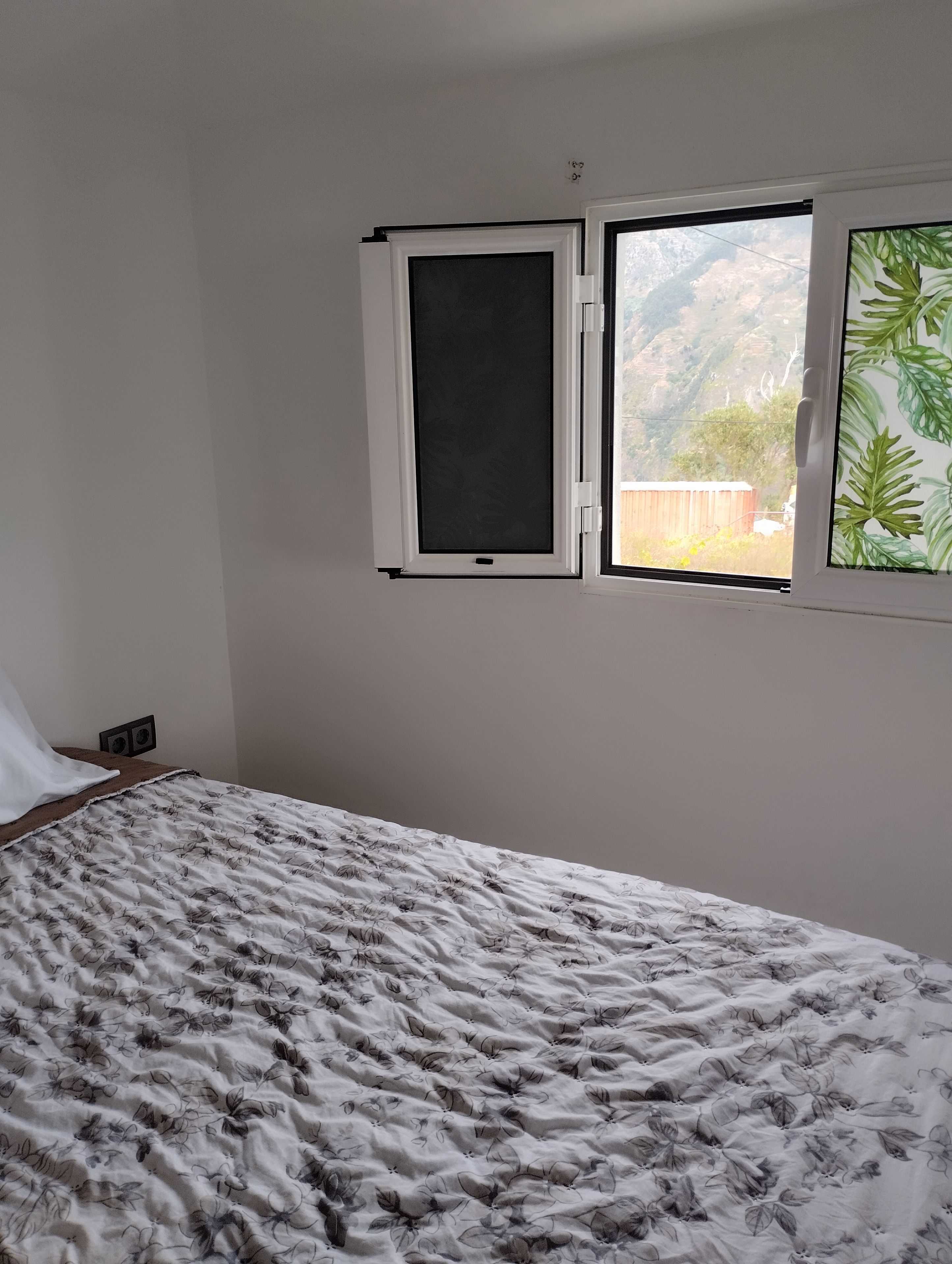 Une chambre à coucher avec un lit, une fenêtre donnant sur un paysage montagneux et un haut-parleur fixé au mur.