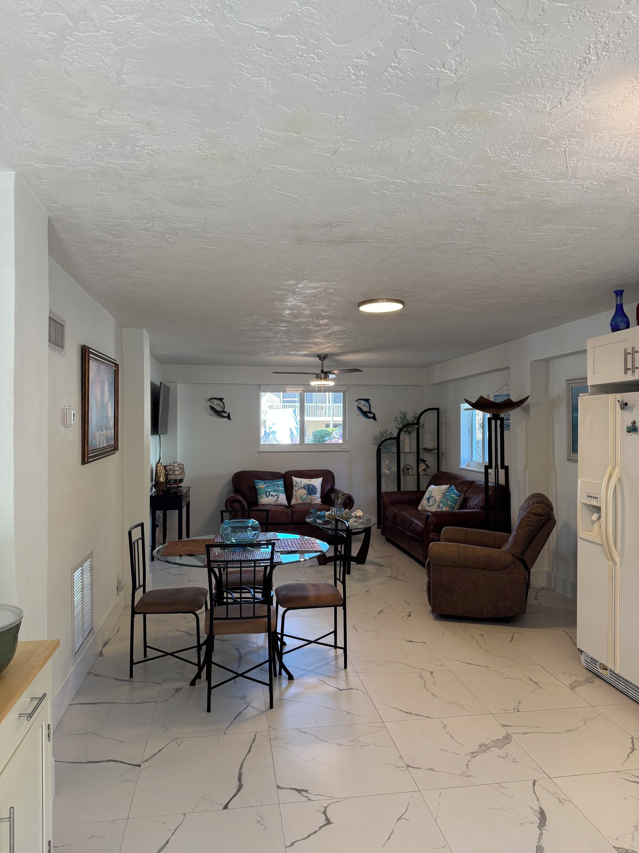 A spacious living area with a dining table, two sofas, and a ceiling fan.