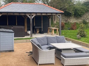 Un área de estar al aire libre techada con una mesa de patio y un sofá.