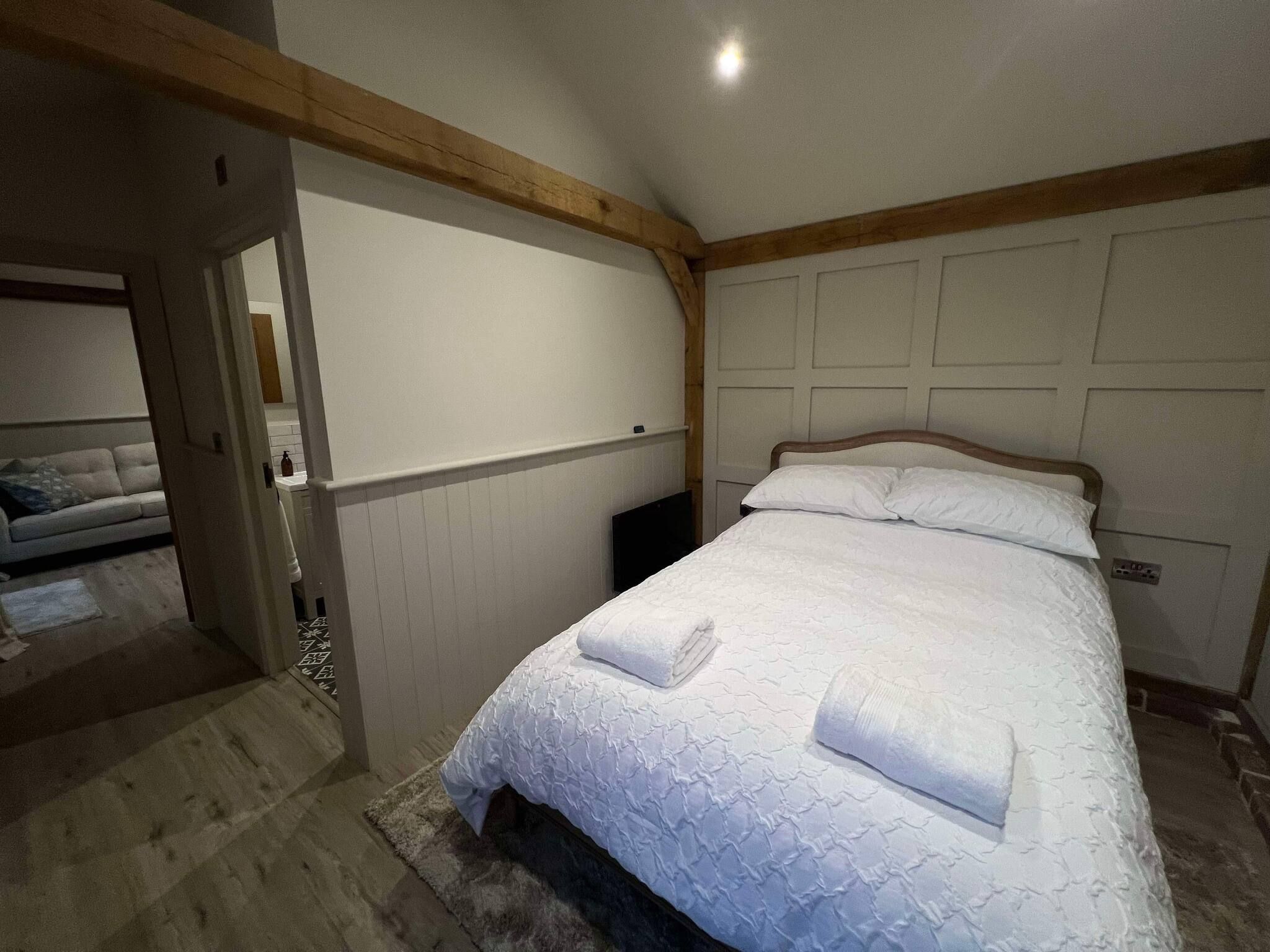 A bedroom with a bed, a nightstand, and a door leading to another room.