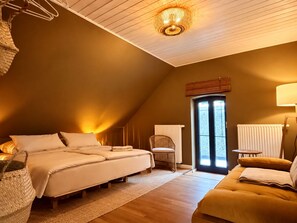 Ein gemütliches Schlafzimmer mit einem Bett, einem Sessel, einer Couch und einem Fenster mit Jalousien.