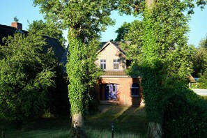 Ein Haus mit Ziegelaußenwand, einer Holzveranda und einer blauen Tür.
