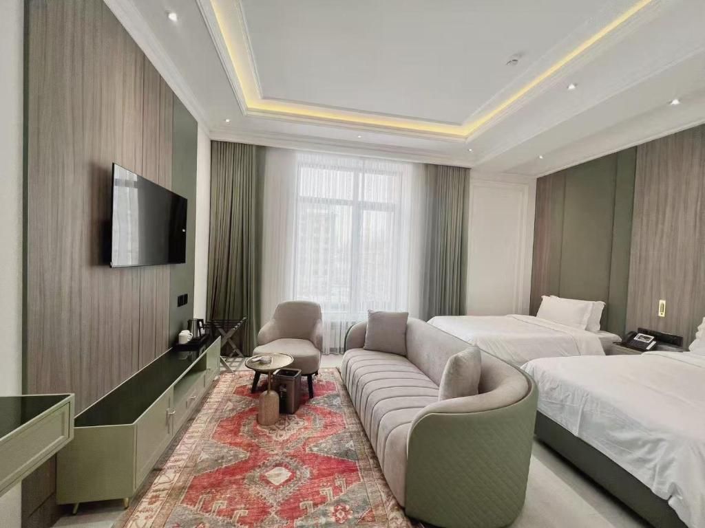 Quarto de hotel moderno com televisão de tela plana, sofá, cama e escrivaninha com cadeira.