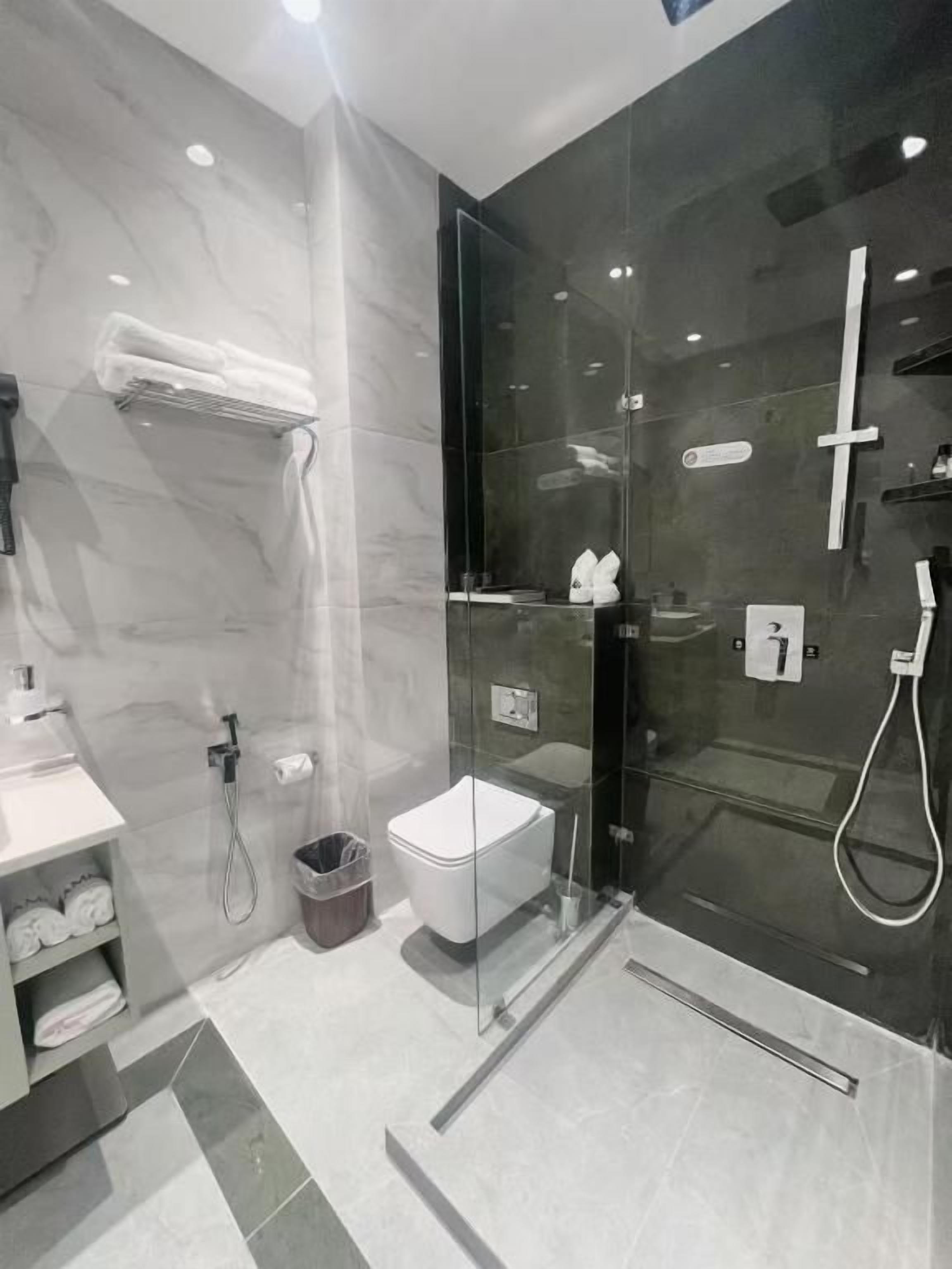Un baño moderno con cabina de ducha de vidrio, inodoro blanco y toallero.