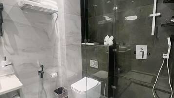 Un baño moderno con cabina de ducha de vidrio, inodoro blanco y toallero.