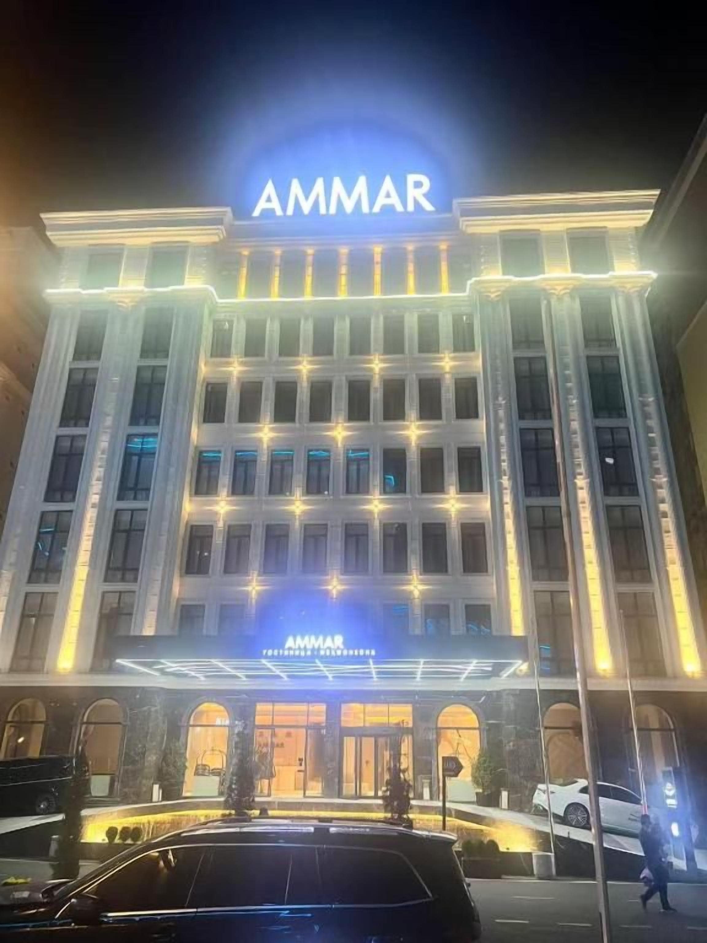 A hotel with a prominent 'AMMAR' sign, large windows, and a well-lit entrance.