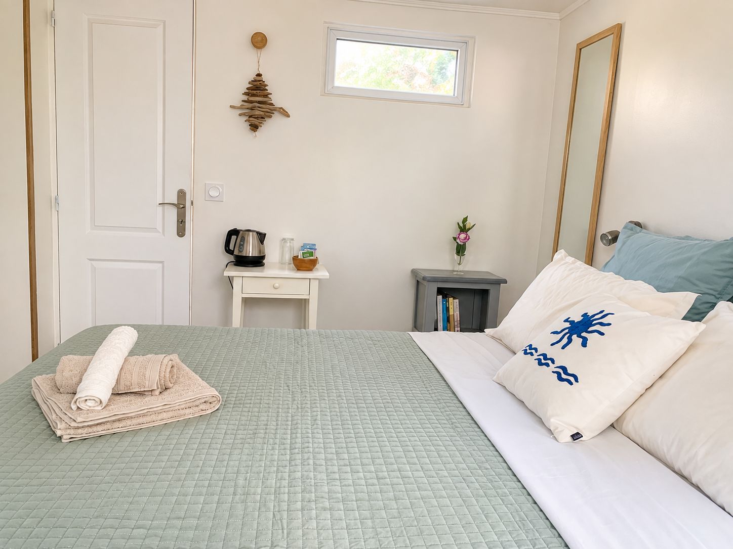 A bedroom with a bed, a nightstand, a window, and a door.