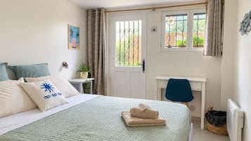 A bedroom with a bed, a desk, a chair, a radiator, and a window with curtains.
