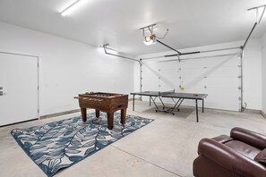A room with a foosball table, ping pong table, and a sofa. - Freedom House on Swan River - 3BR/2BA (Bigfork)