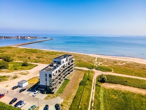 Ein modernes Gebäude mit einer Dachparkfläche und Blick aufs Meer.