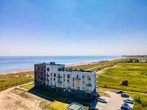 A multi-story building with a flat roof, located near a beach with a clear view of the sea. - Beachloungethree (Kappeln)