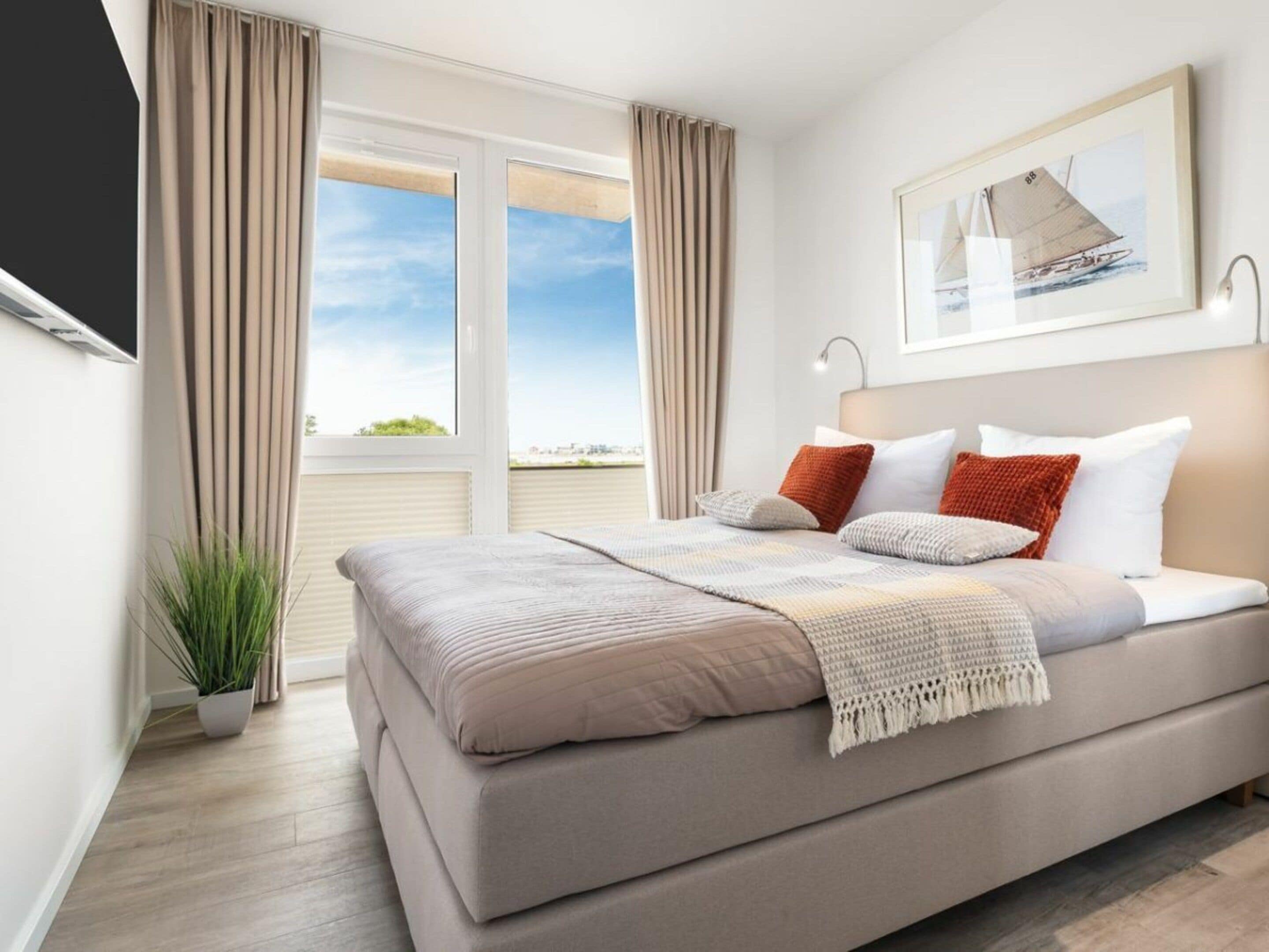 Une chambre à coucher moderne avec un grand lit, une vue sur le ciel et un tableau encadré au mur.
