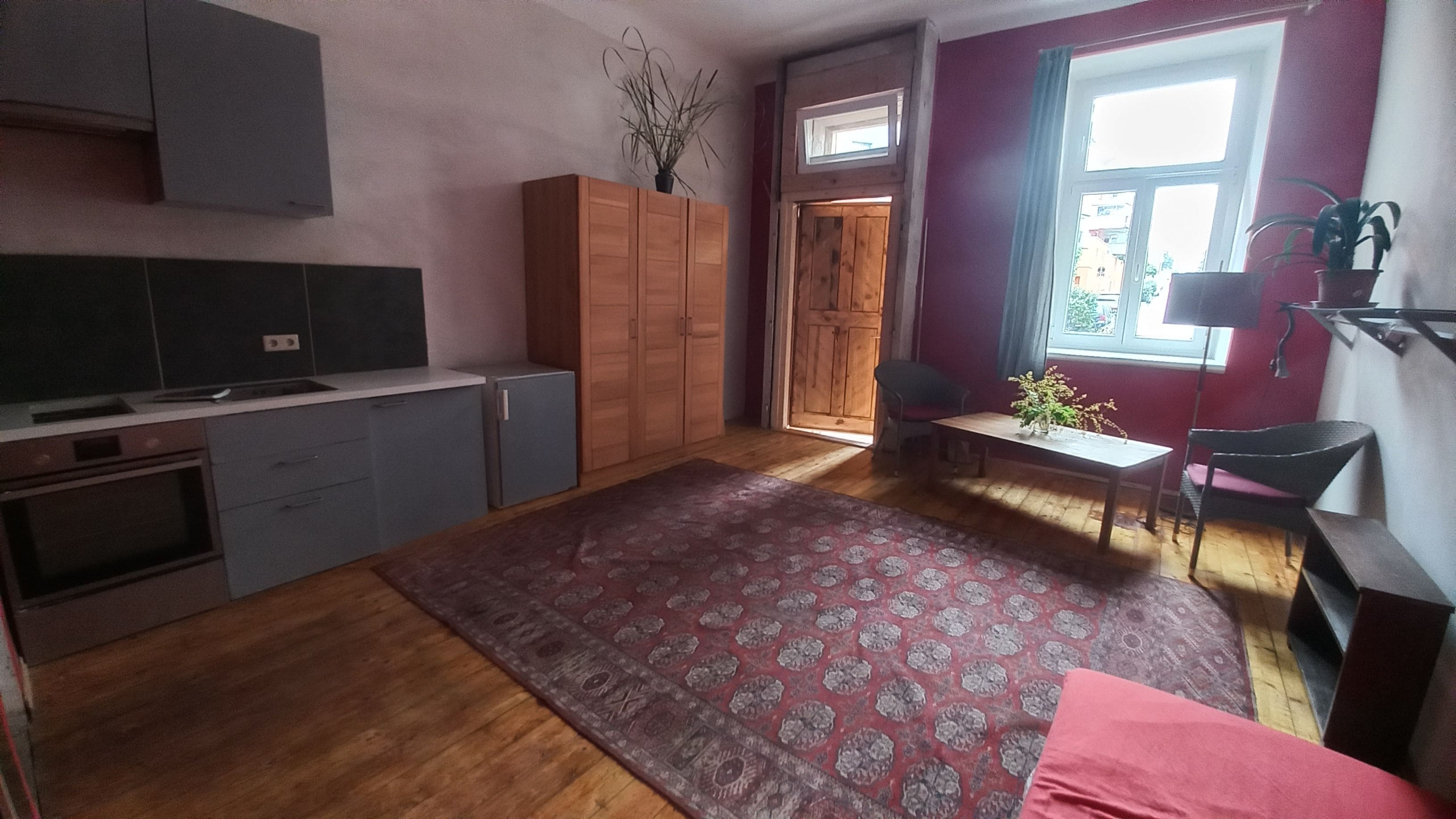 Eine kompakte Küche mit Holzausstattung, einem kleinen Kühlschrank und einem Essbereich mit Tisch und Stühlen.